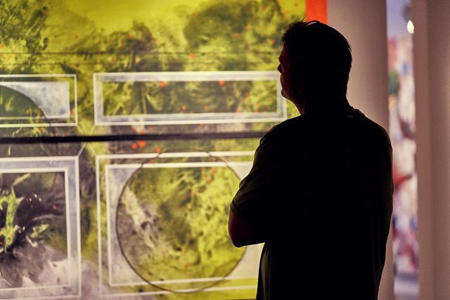 A visitor is silhouetted against a large green painting