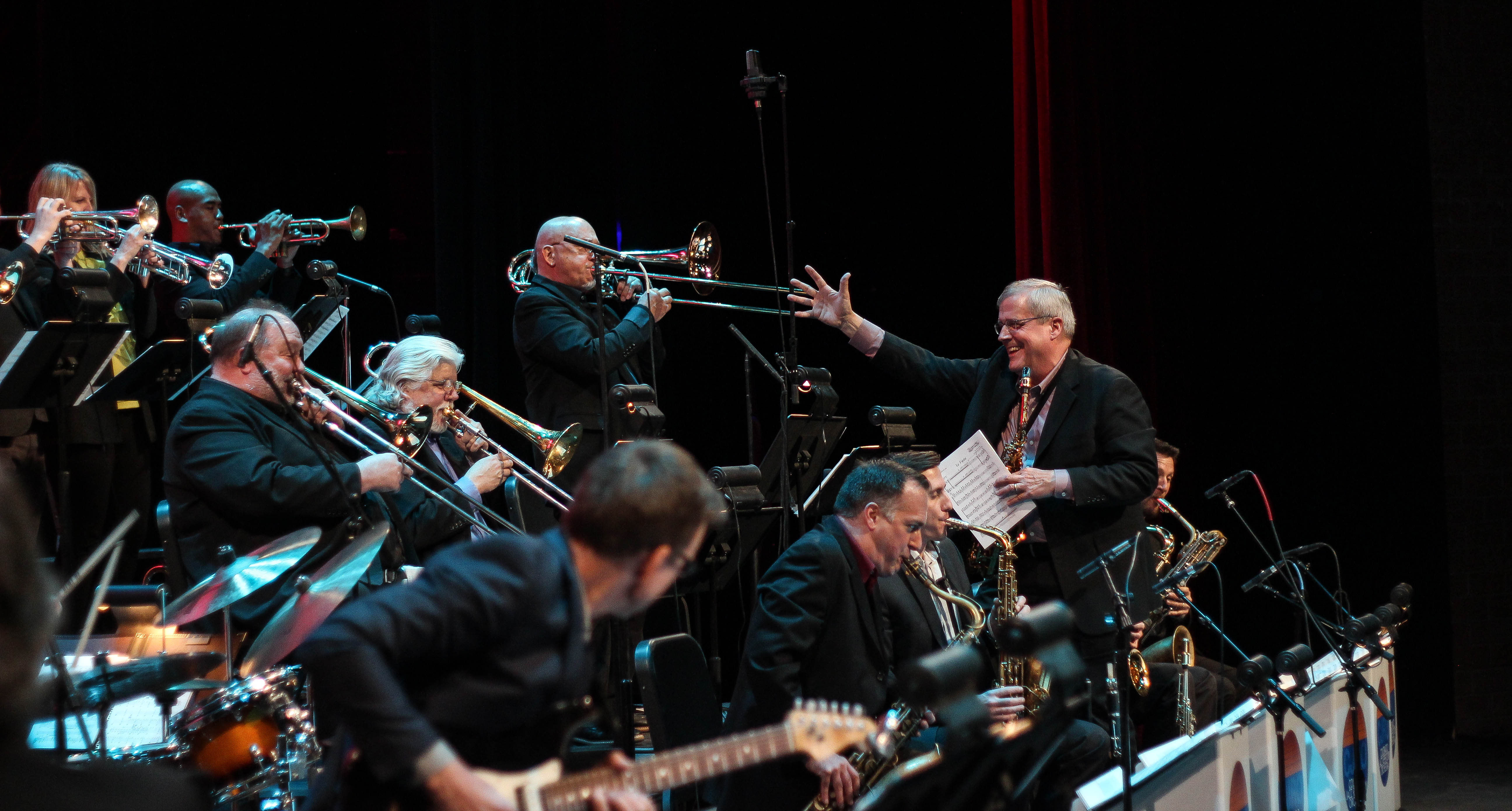 The conductor pointing at the orchestra